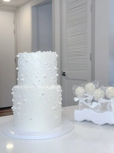 White two-tier cake decorated with pearls of different sizes