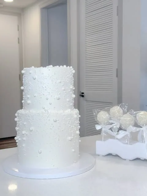 White two-tier cake decorated with pearls of different sizes